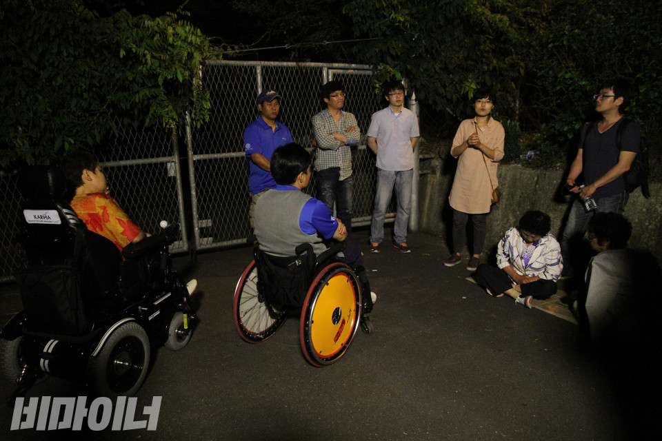 2012년 6월 ‘원주 귀래 사랑의 집’ 앞에서 송효정 활동가가 사람들과 이야기를 나누고 있다. 원주시 공무원과 경찰이 서로에게 책임을 미룰 뿐 아무런 조치를 하지 않은 사이, 밤이 어둑해졌다. 사진 강혜민 