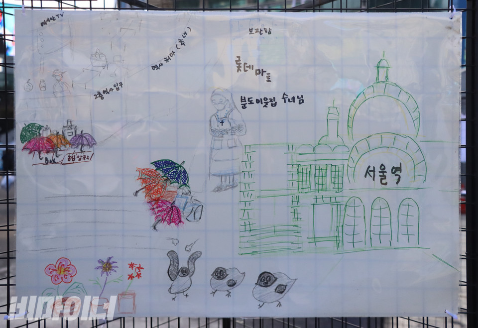 ‘여성홈리스가 나눈 집 이야기’ 전시 중 여성홈리스 당사자 로즈마리(가명) 씨가 그린 심리지도. 작품 왼쪽으로 서울역 대합실에서 휴식을 취하는 홈리스의 모습이 보인다. 역사 바깥에는 형형색색의 우산으로 가려놓은 홈리스의 짐가방이 보인다. 모두 홈리스의 삶에 꼭 필요한 살림살이다. 사진 복건우