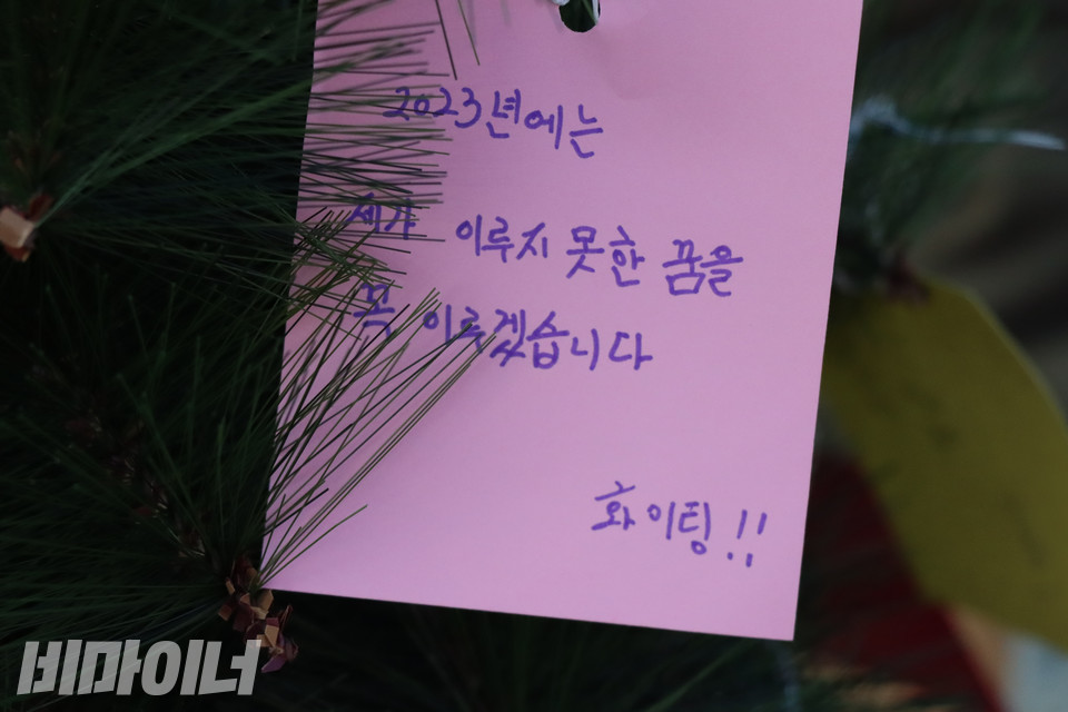 ‘여성홈리스가 나눈 집 이야기’ 전시회 부스에 설치된 크리스마스 트리에 한 홈리스가 달아 놓은 분홍색 메모지가 보인다. ‘2023년에는 제가 이루지 못한 꿈을 꼭 이루겠습니다’라고 적혀 있다. 사진 복건우