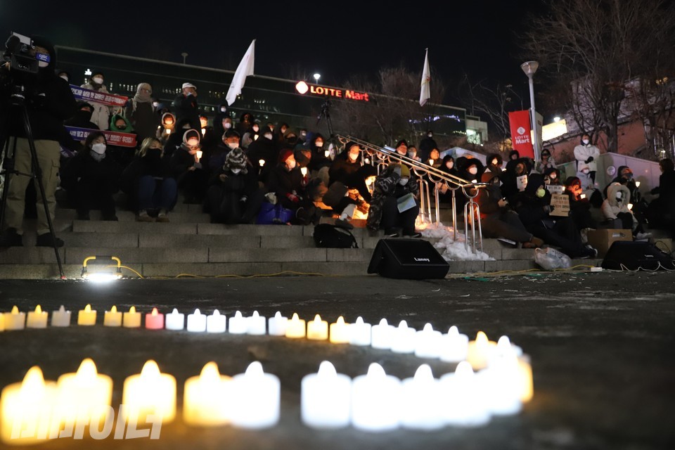 추모제에 참석한 사람들이 서울역 광장 계단에 앉아 있다. 계단 아래에는 하트 모양으로 놓인 초 수십 개가 환하게 불을 밝히고 있다. 사진 하민지
