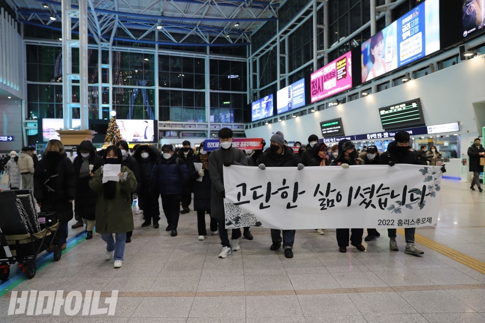 서울역 실내 대합실을 행진하는 기획단. 현수막에 “고단한 삶이셨습니다. 2022 홈리스 추모제”라고 적혀 있다. 사진 하민지