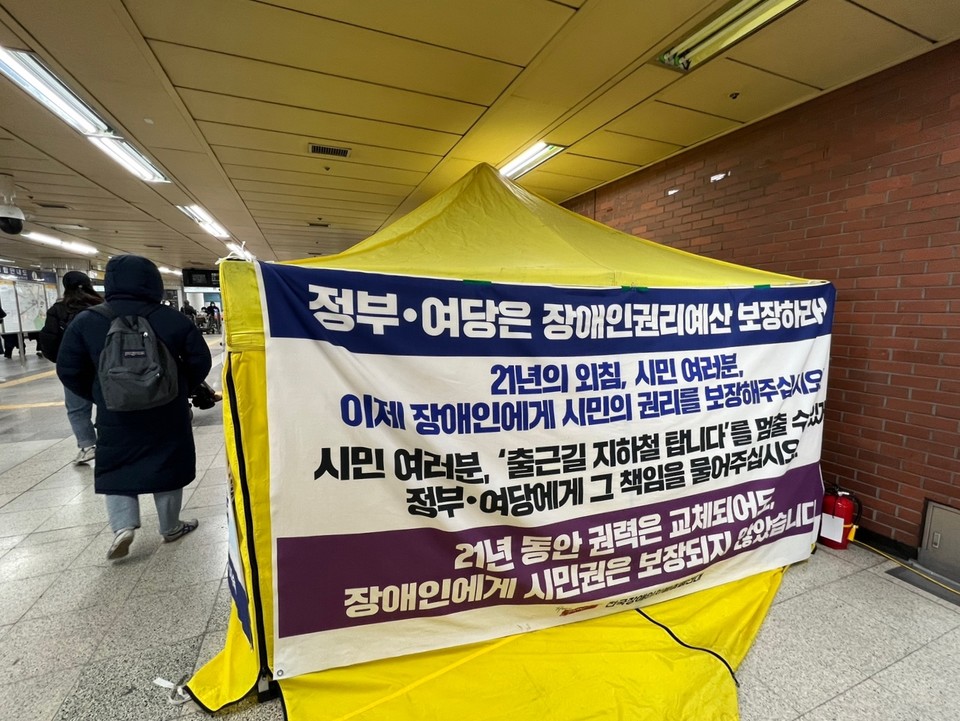농성장 옆면의 모습. ‘정부, 여당은 장애인권리예산 보장하라! 21년의 외침, 시민 여러분, 이제 장애인에게 시민의 권리를 보장해 주십시오. 시민 여러분, 출근길 지하철 탑니다를 멈출 수 있게 정부, 여당에게 그 책임을 물어주십시오. 21년 동안 권력은 교체되어도 장애인에게 시민권은 보장되지 않았습니다’라고 적혀 있다. 사진 임지영 서울시협의회 활동가