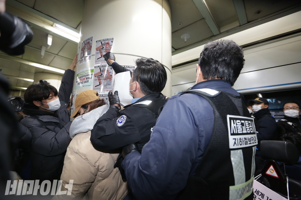 활동가들이 장애인권리예산을 알리는 선전물을 승강장 기둥에 부착하자 서울교통공사 지하철 보안관이 바로 떼어 내고 있다. 사진 강혜민 