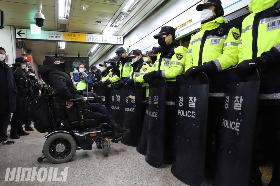 방패로 무장한 경찰이 휠체어 이용자를 막아서고 있다. 사진 하민지