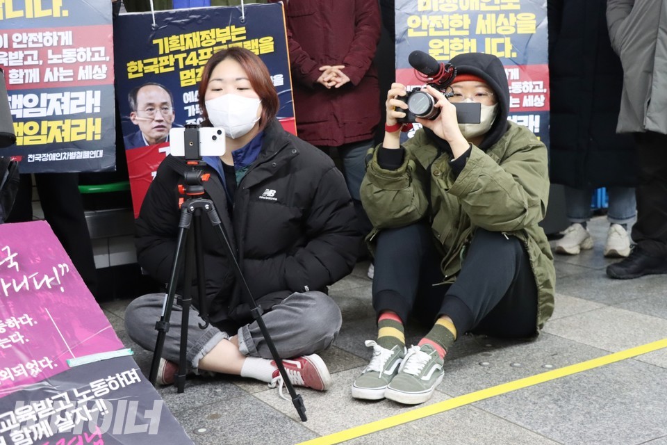 박미주 서울장애인차별철폐연대 활동가가 선전전을 생중계하고 있다. 민아영 영상활동가는 박 활동가 옆에 앉아 발언자를 촬영하고 있다. 사진 하민지