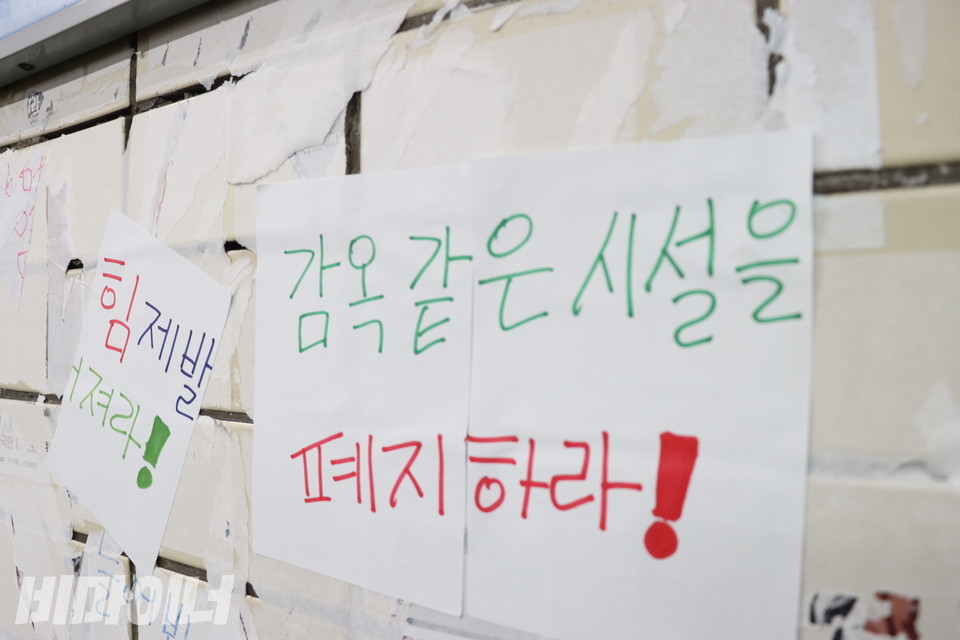 혜화역 벽면. 여기저기 스티커가 뜯긴 흔적이 있다. 그 위에 누군가 A4 종이에 직접 쓴 글씨로 “감옥 같은 시설을 폐지하라!”고 적었다. 사진 강혜민 