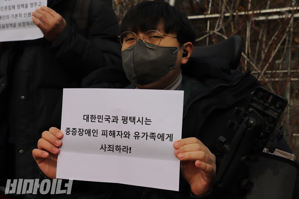 한 활동가가 “대한민국과 평택시는 중증장애인 피해자와 유가족에게 사죄하라!”라고 적힌 손팻말을 들고 있다. 사진 하민지