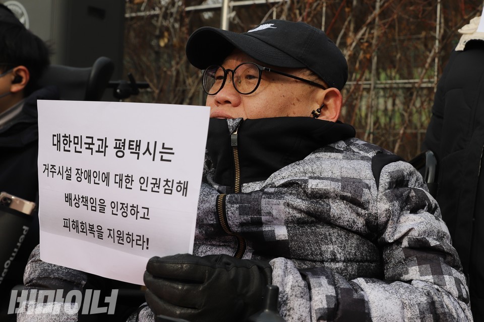 한 활동가가 “대한민국과 평택시는 거주시설 장애인에 대한 인권침해 배상책임을 인정하고 피해회복을 지원하라!”라고 적힌 손팻말을 들고 있다. 사진 하민지