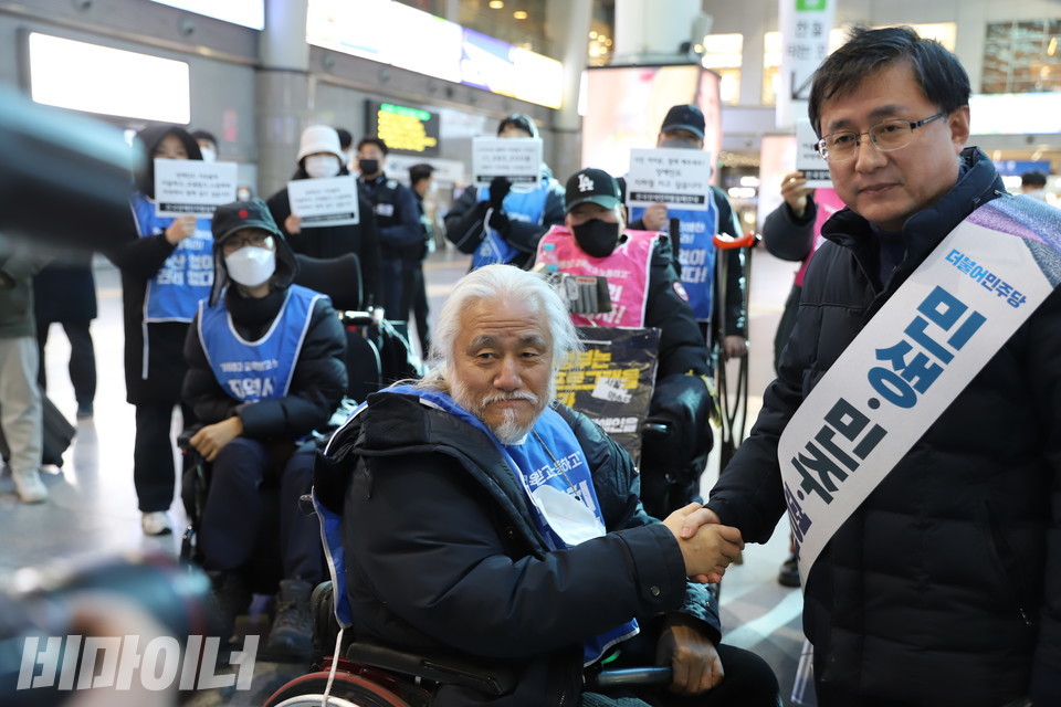 박경석 전장연 상임공동대표와 김성환 더불어민주당 정책위의장이 악수하며 사진을 찍고 있다. 사진 하민지