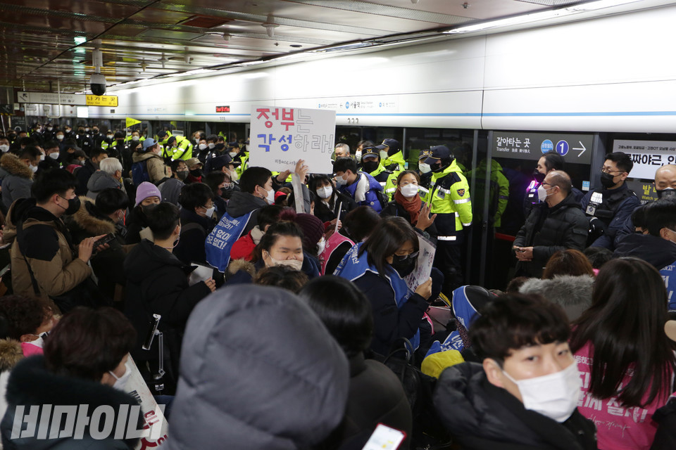 지하철행동을 위해 모인 전장연 활동가와 시민, 이를 가로막는 서울교통공사 보안관과 경찰로 승강장이 가득 찼다. 그 사이로 피플퍼스트서울센터 활동가가 직접 만든 피켓 “정부는 각성하라”가 보인다. 사진 강혜민
