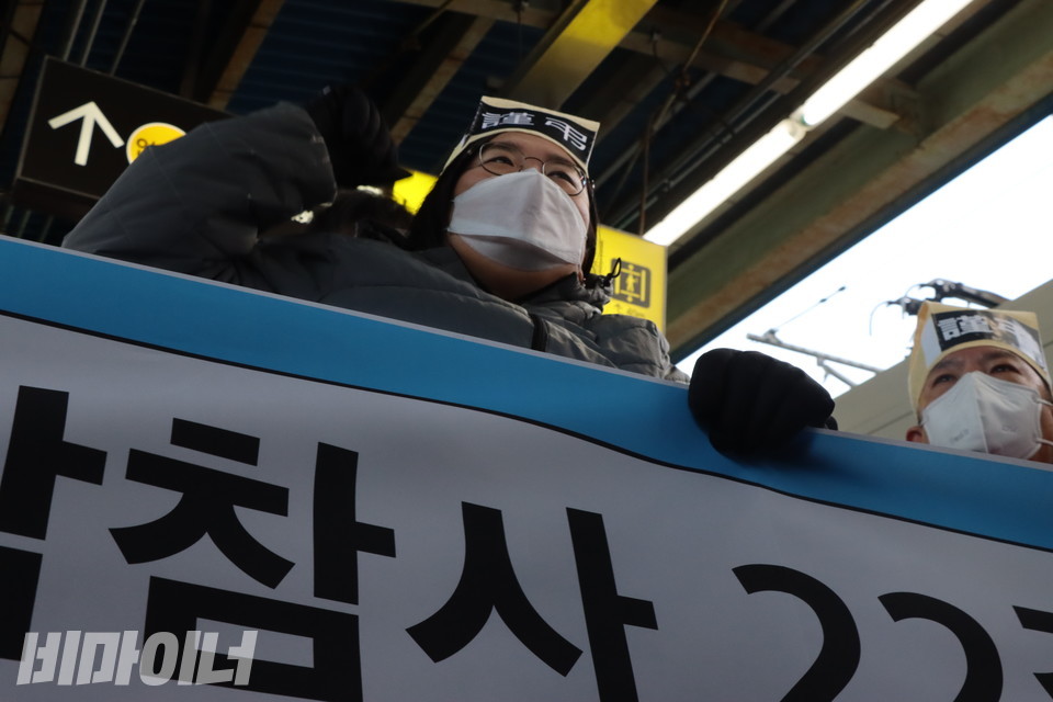 20일 오전 서울 지하철 4호선 오이도역 승강장 앞에서 김선영 나무를심는장애인야학 교장(왼쪽)이 왼손으로 파란색 현수막을 잡고 오른손 주먹을 불끈 쥐어 보이며 정면을 응시하고 있다. 사진 복건우