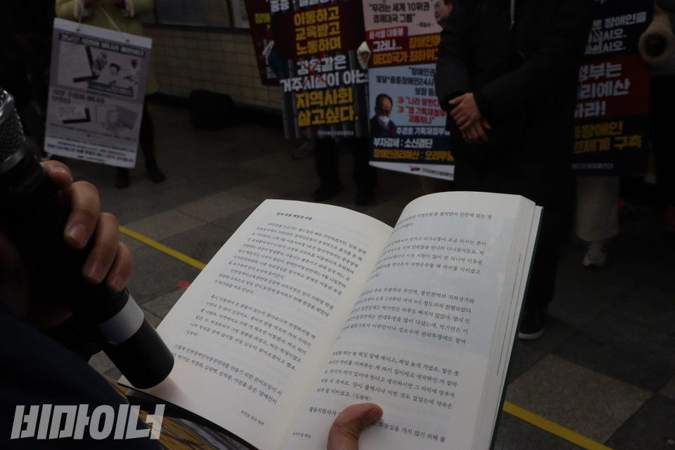 전국장애인차별철폐연대가 25일 오전 서울지하철 4호선 혜화역(동대문 방면) 5-4 승강장에서 출근길 지하철 선전전을 진행하며 비마이너가 기획한 책 『유언을 만난 세계』를 낭독하고 있다. 장애인 이동권과 활동지원서비스 제도화를 위해 투쟁한 박기연 열사의 생애를 다룬 대목이 펼쳐져 있다. 사진 복건우