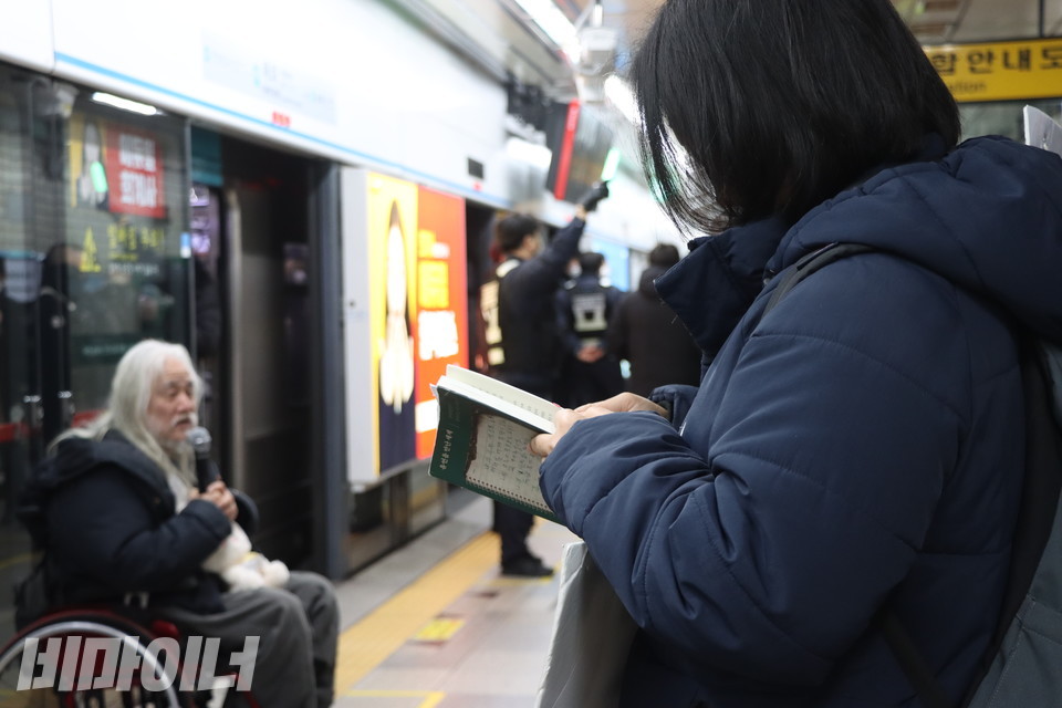 박경석 대표가 발언하는 동안 정다운 활동가가 『유언을 만난 세계』 책을 훑어보고 있다. 사진 강혜민