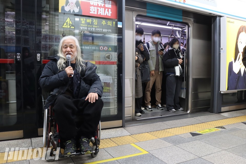박경석 전장연 상임공동대표가 발언하고 있다. 열린 지하철 문 안으로 승강장을 바라보고 있는 시민들이 보인다. 사진 하민지 