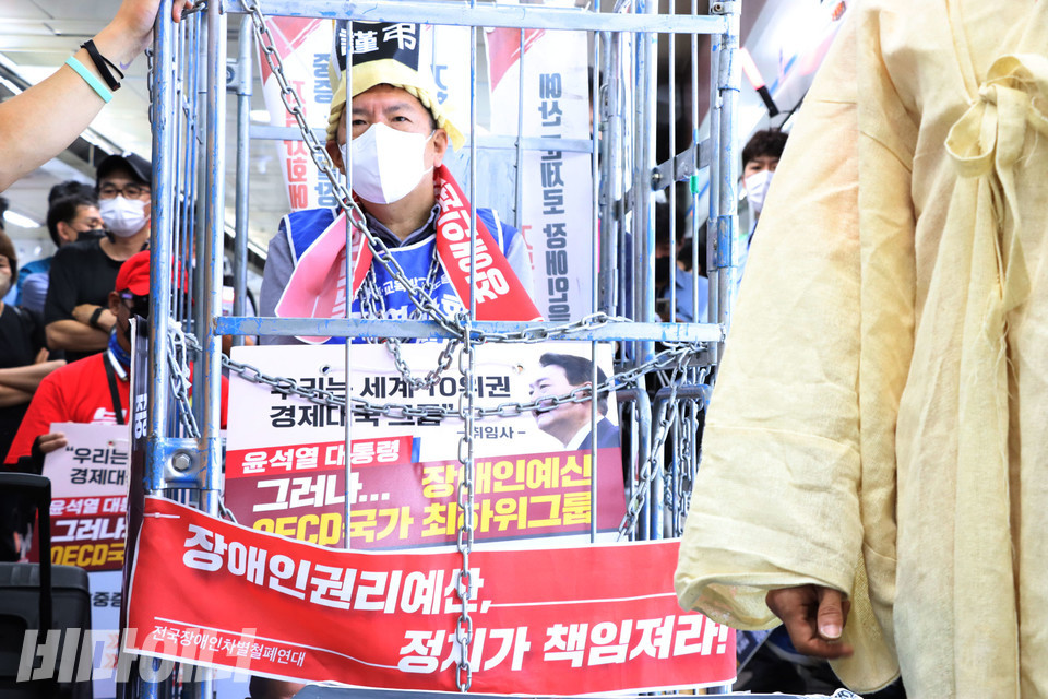 철창 안에 갇힌 권달주 대표. 철창엔 “장애인권리예산, 정치가 책임져라!”고 적힌 피켓이 걸려있다. 사진 강혜민