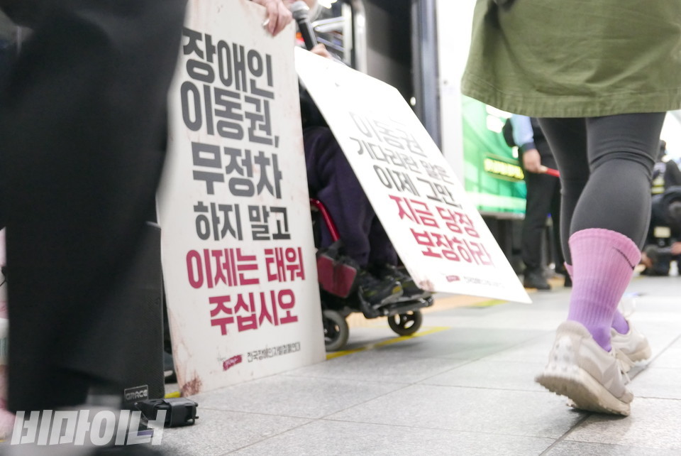선전전을 하는 휠체어 이용 장애인들 앞을 걸을 수 있는 시민 두 명이 지나가고 있다. 사진 양유진