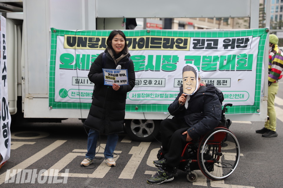 최한별 한국장애포럼 사무국장(왼쪽)과 오세훈 서울시장 가면을 쓴 박경석 전장연 상임공동대표(오른쪽). 사진 하민지