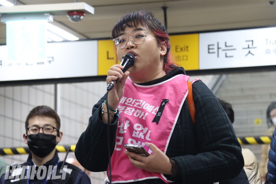 한명희 전장연 활동가가 기자회견을 진행하고 있다. 분홍 몸피씨를 입은 그의 왼쪽 가슴에는 ‘추모’라고 적힌 검은 리본이 있다. 사진 강혜민