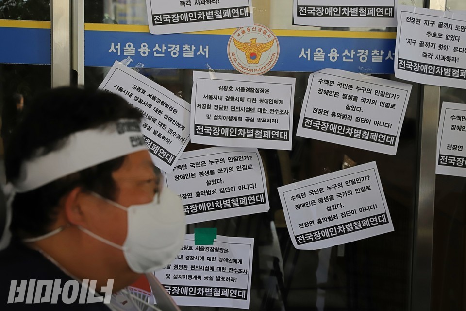 지난해 7월 19일, 이형숙 서울시장애인자립생활센터협의회 회장이 용산서 정문 앞에 있다. 정문에는 ‘김광호 서울경찰청장은 서울시 내 경찰서에 대한 장애인에게 제공할 정당한 편의시설에 대한 전수조사 및 설치이행계획 공식 발표하라’고 적힌 피켓이 붙어 있다. 사진 하민지