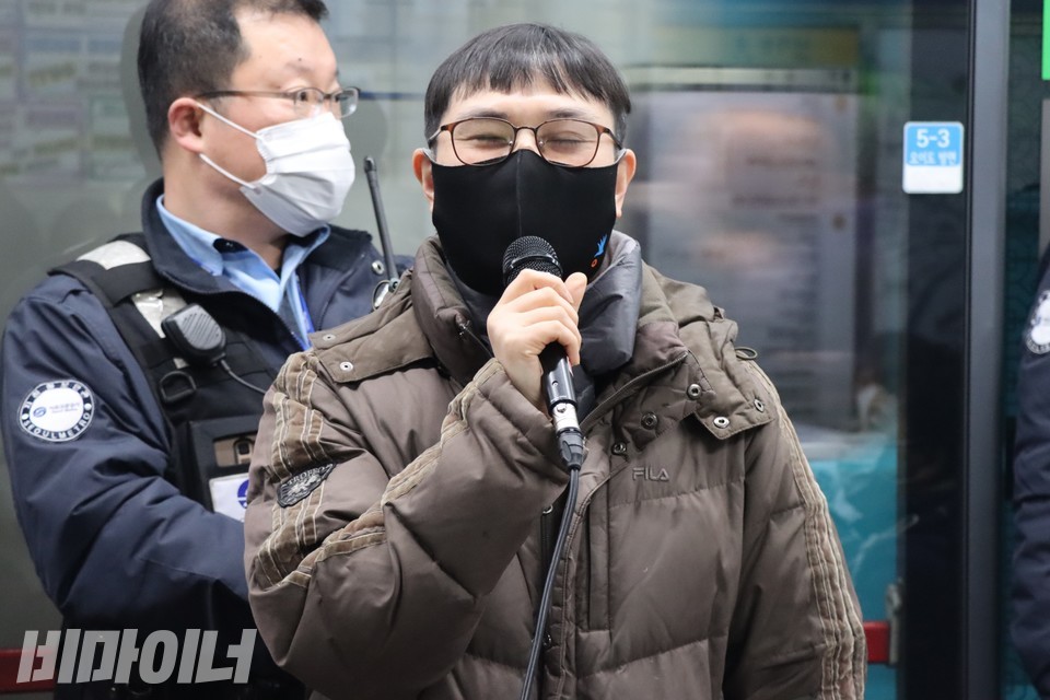 김재왕 희망을만드는법 변호사가 기자회견에서 발언하고 있다. 김 변호사 뒤로 열차가 지나가고 있고 그 앞에 서울교통공사 직원이 서 있다. 사진 복건우