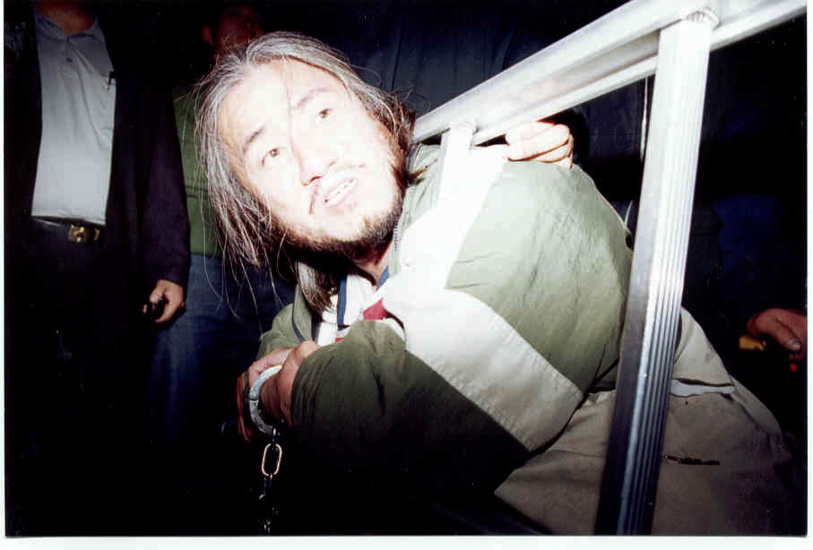 2001년 10월 31일, 버스타기 투쟁 중 박경석 대표가 사다리를 목에 걸고 경찰의 진압에 항의하고 있다. 사진 장애인이동권연대
