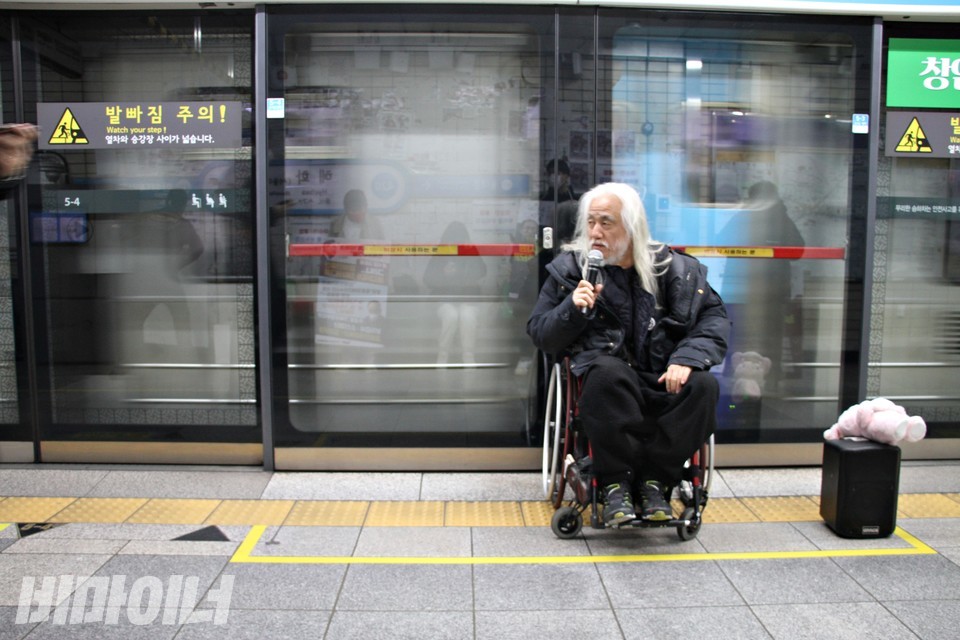 박경석 전장연 상임공동대표가 발언 중이다. 그의 뒤로 열차가 지나가고 있다. 사진 강혜민