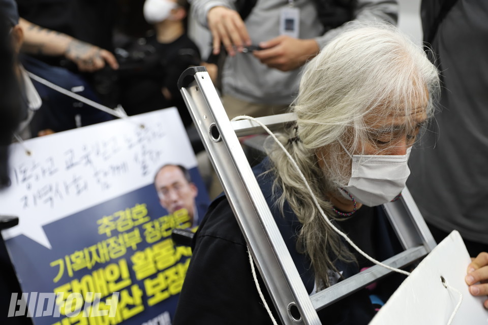 지난해 6월, 박경석 전장연 대표가 지하철 시위를 하고 있다. 그의 목에는 사다리가 걸려 있다. 사진 비마이너DB