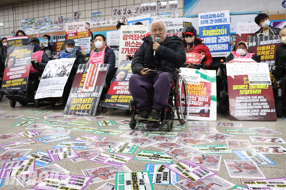 지난 14일, 삼각지역에서 박경석 전장연 대표가 발언하고 있다. 바닥에는 스티커가 가득 붙어 있다. 사진 강혜민