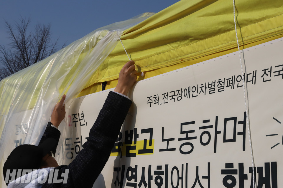 23일 오전 기자회견을 마친 뒤 전국장애인야학협의회 활동가가 국회 앞에 설치된 장애인평생교육법 농성장을 정리하기 위해 비닐과 밧줄을 잡아당기고 있다. 사진 복건우