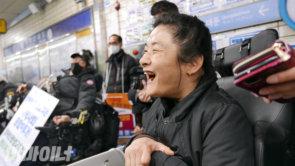 지난 22일 오전 8시, 혜화역 승강장 선전전에서 조상지 씨가 의사소통보조기구(AAC)로 발언하던 중 활짝 웃고 있다. 사진 양유진