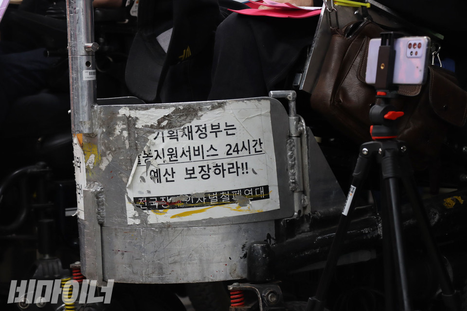 이규식 서울장애인차별철폐연대 대표의 휠체어 앞에 “기획재정부는 활동지원서비스 24시간 예산 보장하라”는 피켓이 헤진 채 붙어 있다. 사진 강혜민