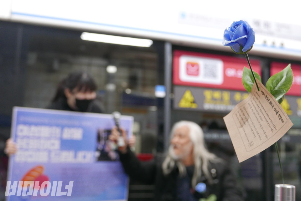 박경석 전장연 상임공동대표가 한여전 활동가에게 마이크를 건네고 있다. 오른쪽에 푸른 장미가 보인다. 사진 양유진