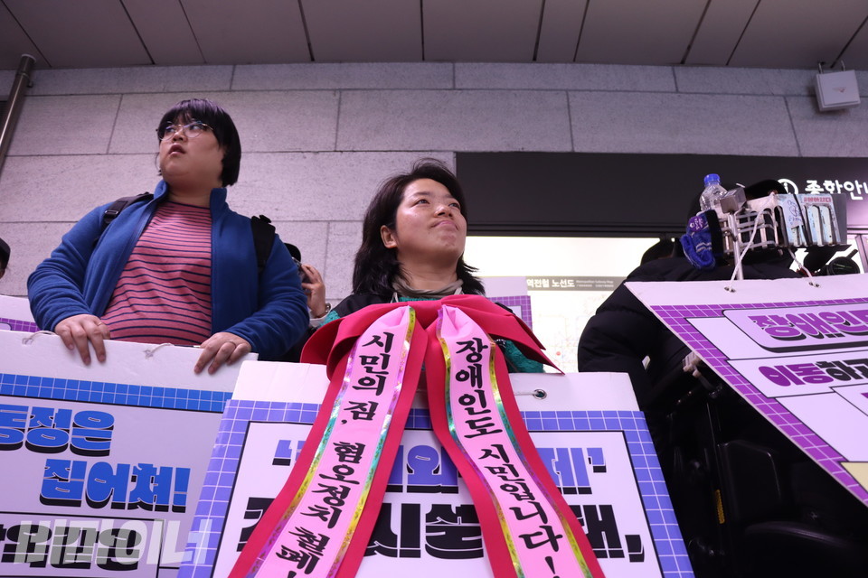 10일 오전 서울지하철 1호선 시청역 승강장에서 문애린 이음장애인자립생활센터 소장이 ‘시민의 짐, 혐오정치 청폐! 장애인도 시민입니다!’라고 적힌 빨간 리본을 목에 단 채 웃어 보이고 있다. 사진 복건우