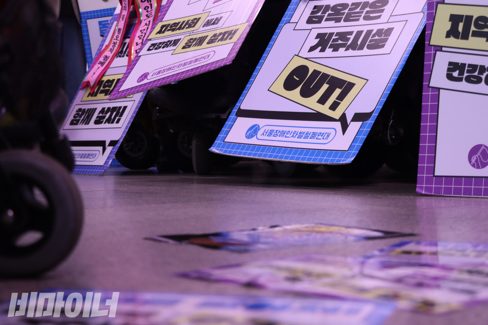 10일 오전 서울지하철 1호선 시청역 승강장 바닥에 붙은 스티커와 전국장애인차별철폐연대 휠체어에 걸린 피켓들. 사진 복건우