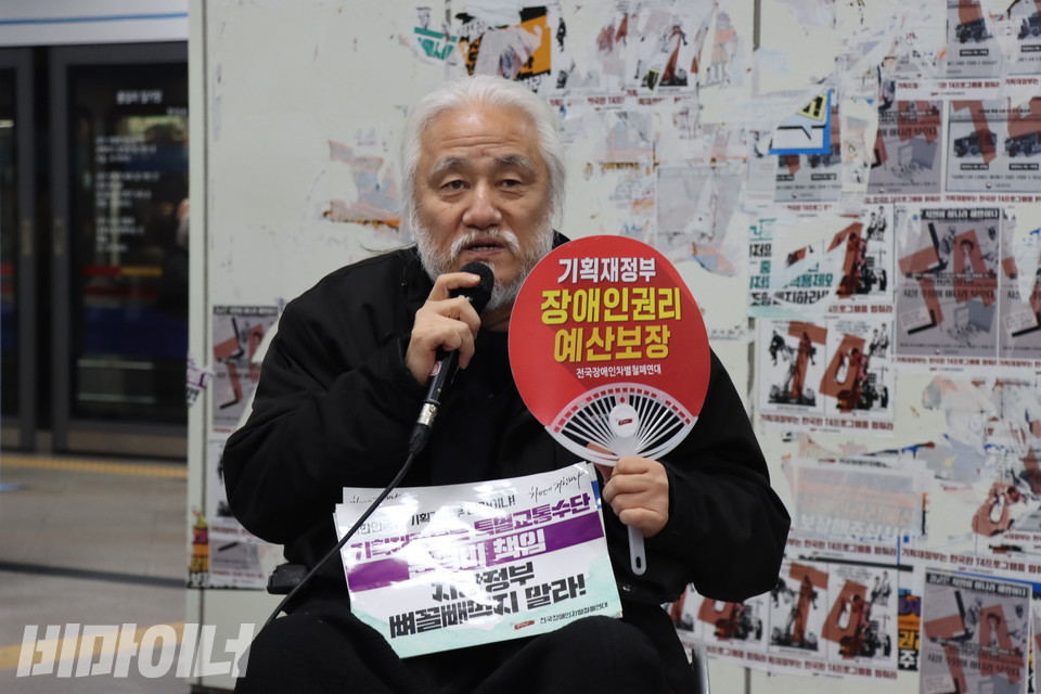 전장연은 장애인정책조정위원회가 열리기 전인 9일 8시, 삼각지역에서 기자회견을 열고 6차 종합계획에 대해 우려를 표했다. 박경석 전장연 상임공동대표가 “기획재정부 장애인권리예산 보장”이라고 적힌 빨간 부채를 들고 발언 중이다. 사진 하민지