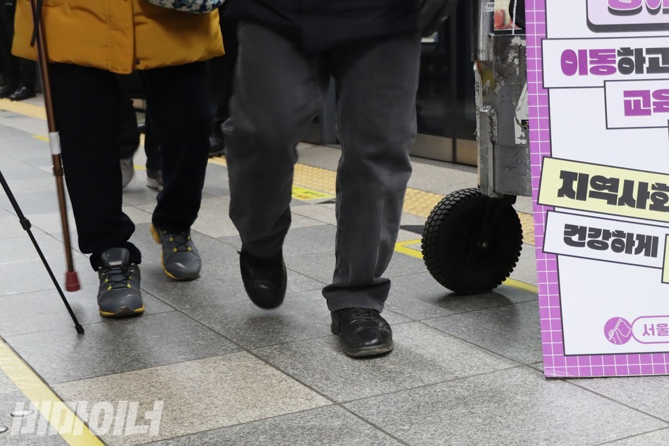 지팡이를 짚은 노인들이 이규식 서울장애인차별철폐연대 상임대표의 휠체어 앞을 지나가고 있다. 사진 하민지