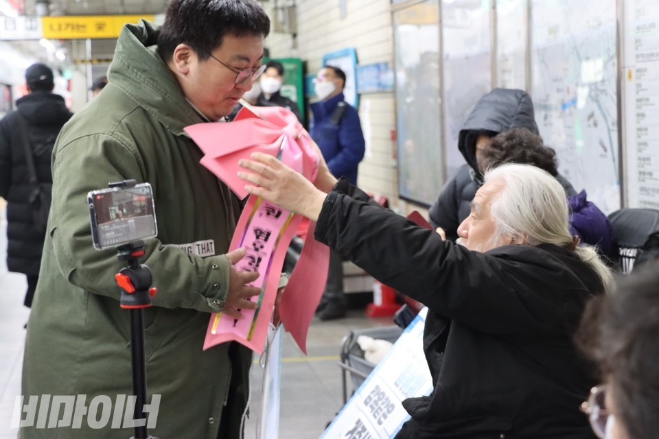 박경석 전장연 상임공동대표가 박철균 전장연 활동가 목에 리본을 걸어주고 있다. 사진 하민지