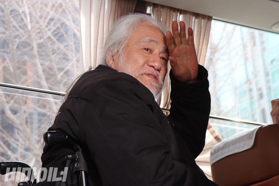 호송차량에 탑승한 박경석 전장연 상임공동대표가 활동가들에게 인사하고 있다. 사진 하민지