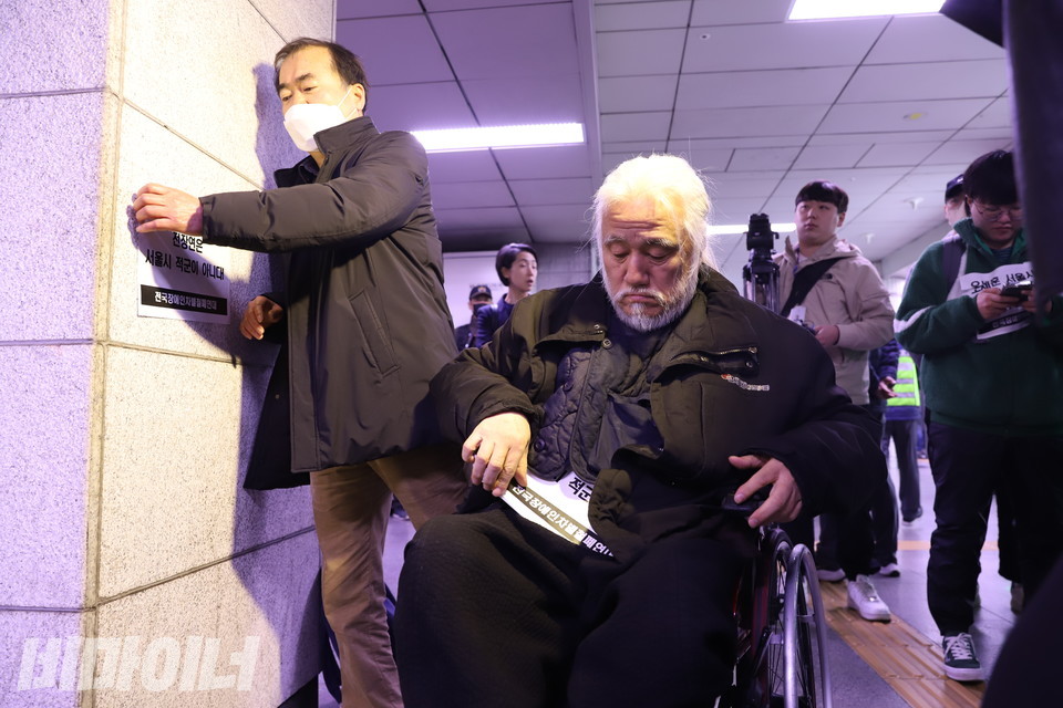 박경석 대표가 벽에 스티커를 붙이자 서울교통공사 직원이 바로 떼어내고 있다. 사진 강혜민