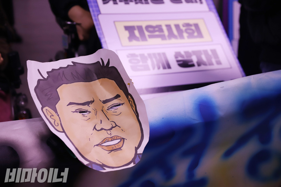 현수막에 붙어 있는 오세훈 서울시장 캐리커처. 그 뒤로 “지역사회 함께 살자”는 문구가 흐릿하게 보인다. 사진 강혜민