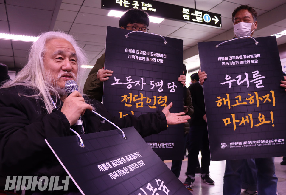 22일 오전 서울지하철 1호선 시청역 청량리 방면 승강장에서 박경석 전국장애인차별철폐연대 상임공동대표(왼쪽)가 왼손으로 피켓을 가리키며 권리중심중증장애인맞춤형공공일자리에 대해 설명하고 있다. 사진 복건우