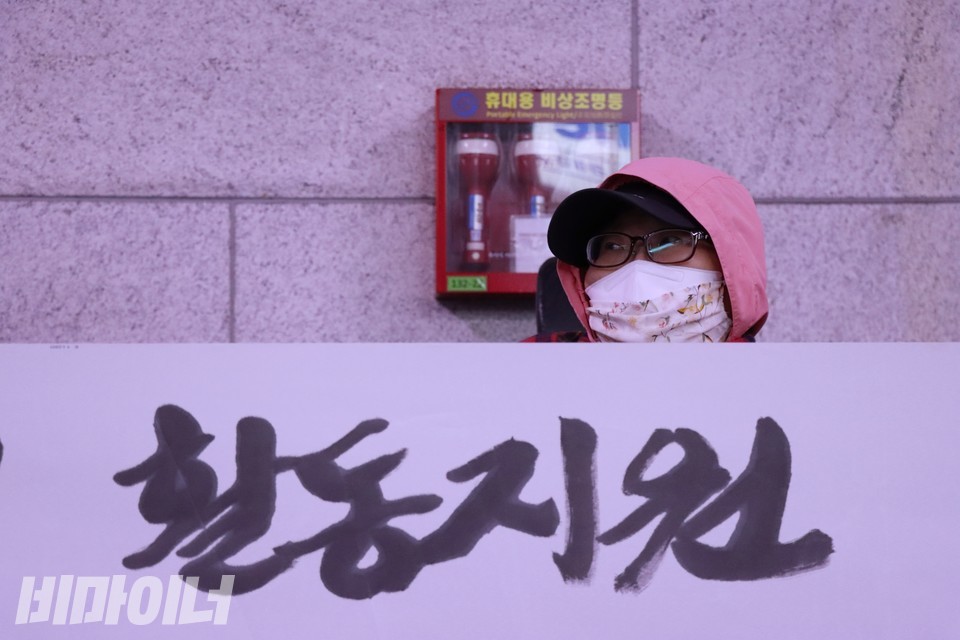 전장연은 지난 20일 오전 8시, 1호선 시청역에서 ‘서울시 장애인활동지원 표적조사 거부’ 기자회견을 열었다. 이수미 노들장애인야학 학생이 기자회견에 참여 중이다. 그의 앞에 펼쳐진 현수막에는 “활동지원”이라 적혀 있다. 사진 하민지