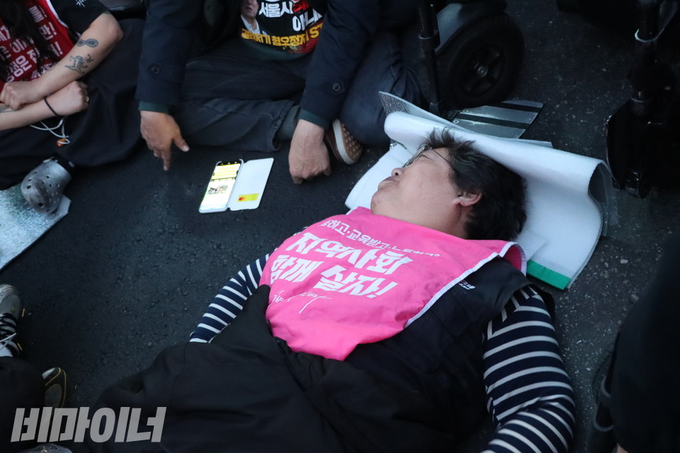 휠체어에서 내려와 바닥에 누워 시위 중인 이형숙 서울시장애인자립생활센터협의회 회장. 사진 하민지