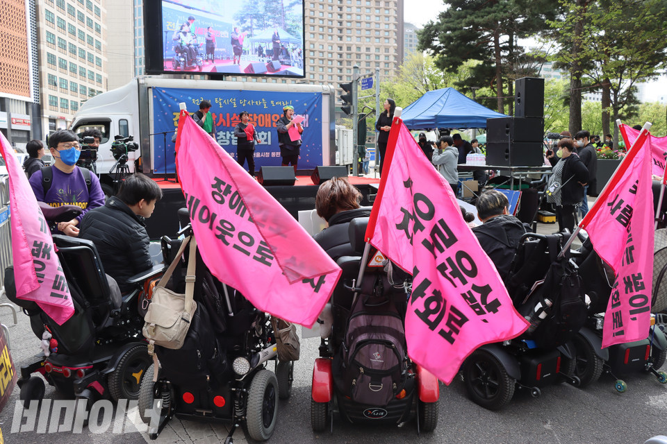 13일 오후 서울시청 동편 도로에서 열린 전국탈시설장애인연대 창립대회에 참여한 장애인들이 붉은 깃발을 휠체어 뒤에 꽂은 채 무대를 지켜보고 있다. 사진 복건우