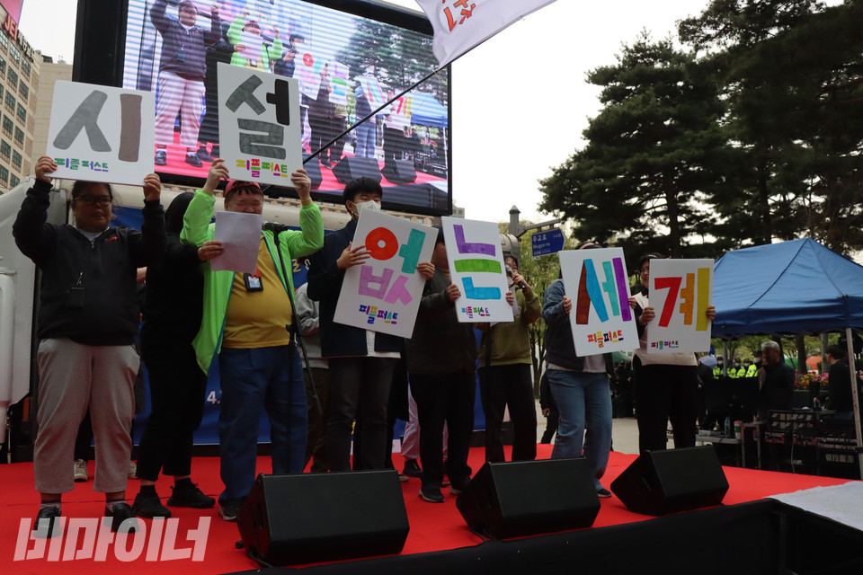 13일 오후 서울시청 동편 도로에서 열린 전국탈시설장애인연대 창립대회에 참여한 서울피플퍼스트 활동가들이 ‘시설 없는 세계’가 한 글자씩 적힌 형형색색의 피켓을 들고 유엔탈시설가이드라인을 낭독하고 있다. 사진 복건우