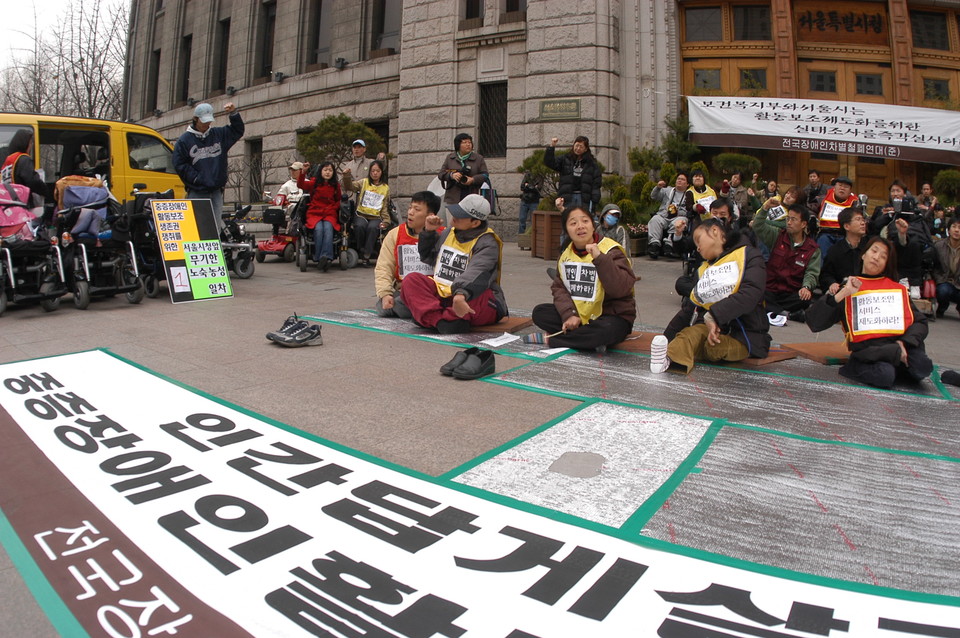 2006년 3월 20일, 전국장애인차별철폐연대 준비위원회가 서울시청 앞에서 활동보조 제도화를 요구하며 노숙농성에 돌입했다. 천막도 없이 바닥에 은박스티로폼만 깔고서 농성 돌입을 선포하는 장애인 활동가들. 사진 김유미