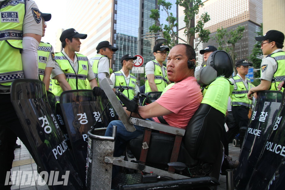 2015년 5월 28일, 장애등급제·부양의무제 폐지 공동행동은 도심 곳곳 도로를 막는 ‘그린라이트 투쟁’을 벌였다. 광화문 사거리를 점거하던 이규식이 경찰에 둘러싸여 있다. 사진 강혜민