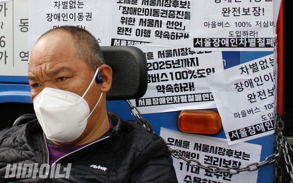 보궐선거 하루 전인 2021년 4월 6일, 당시 오세훈 국민의힘 서울시장 후보를 향해 장애인들이 이동권 완전 보장을 촉구하며 출근길 버스를 점거했다. 버스와 자신의 휠체어를 쇠사슬로 묶고 버스를 점거 중인 이규식. 사진 하민지 