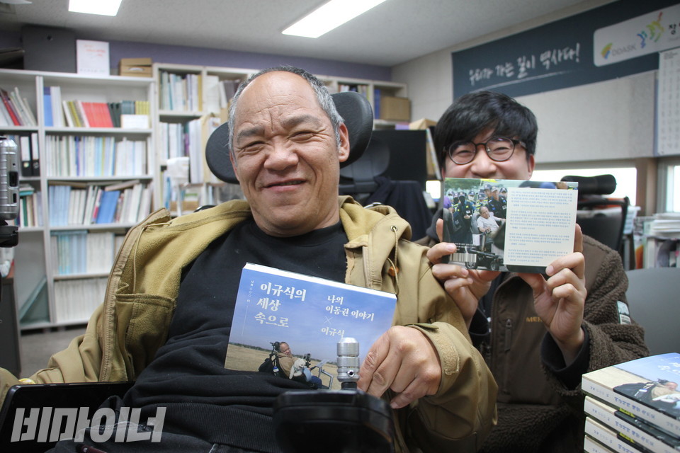 이규식과 이 책 공동저자 중 한 사람인 김형진이 『이규식의 세상 속으로』를 들고 환하게 웃고 있다. 김형진은 이규식의 10년 차 활동지원사다. 사진 강혜민