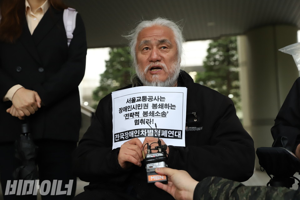 박경석 전장연 대표가 발언하고 있다. 그의 손에는 “서울교통공사는 장애인 시민권 봉쇄하는 전략적 봉쇄소송 멈춰라”고 적힌 피켓이 들려 있다. 사진 강혜민 
